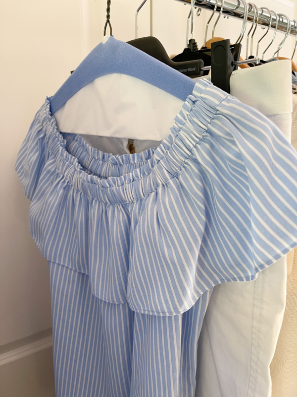 Striped off shoulder top and white Bermuda shorts on hanging rack for Napa Valley trip.