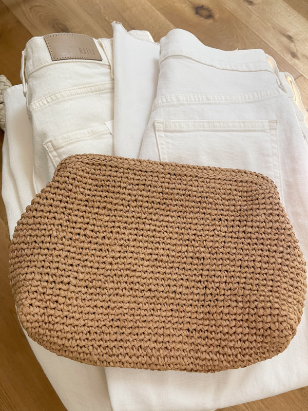 Two pair of white jeans and a woven clutch ready to pack for NAPA VALLEY.