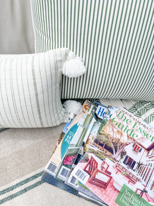 Magazine tossed onto outdoor sofa next to green and white pillows