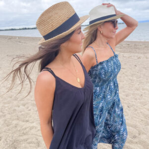 Two women wearing hats and Change of Scenery dresses walking on beach.