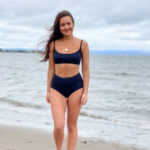 Woman wearing two-piece Change of Scenery swimsuit on beach.