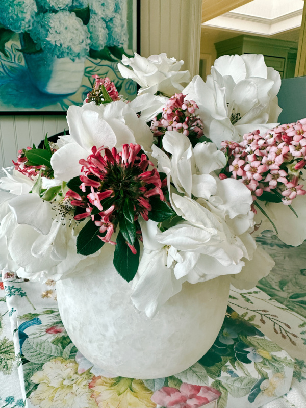 Vase of white roses and pink stems.