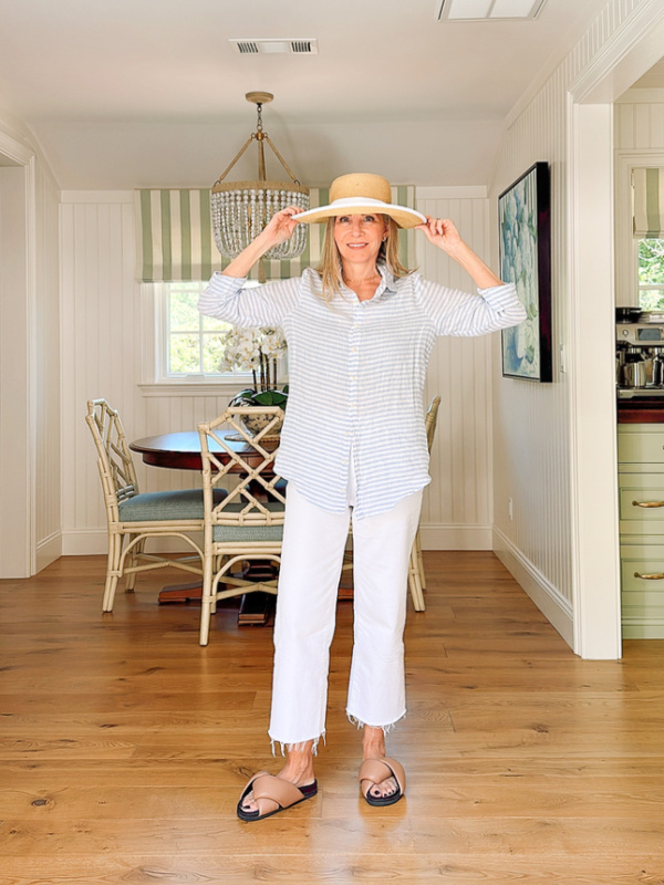 Woman wearing white jeans, striped shirt and sun hat.