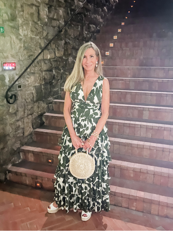woman standing in wine cellar wearing green and white dress.