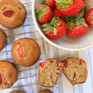 Strawberry muffins next to bowl of strawberries.