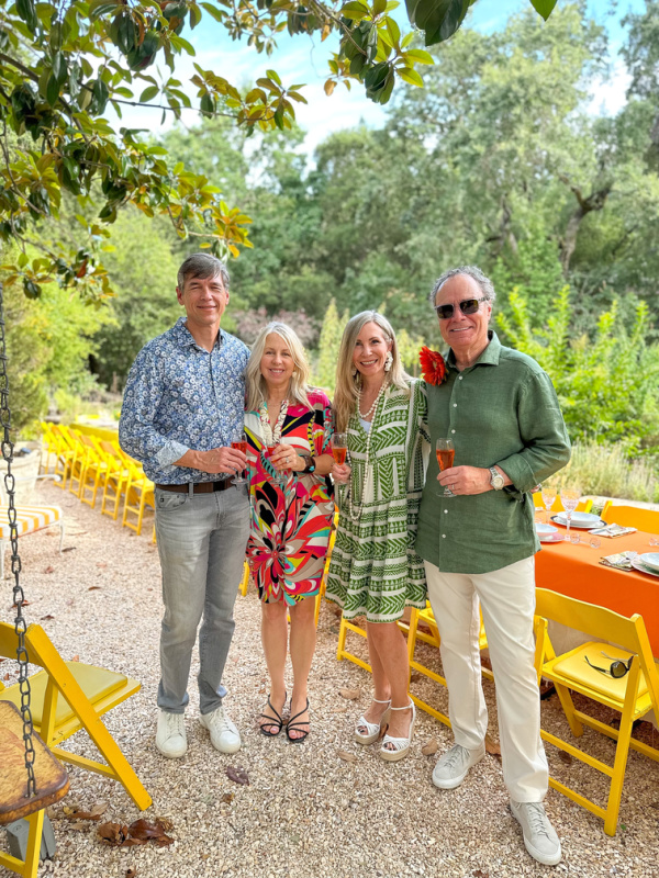 Two couples posing together holding Aperol Spritz at garden party.
