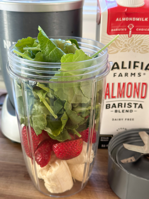 Ingredients for kale strawberry smoothie packed into jar of Nutra Bullet.