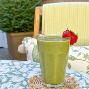 Kale and strawberry smoothy sitting on outdoor dining table.