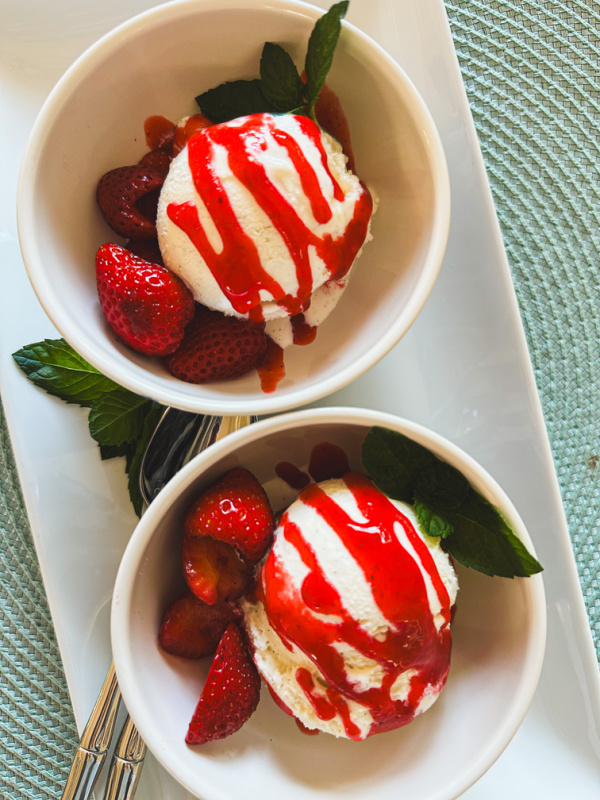 Cups of ice cream drizzled with strawberry puree.