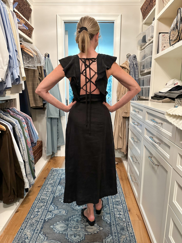 woman trying on little black dress with lace up detail.