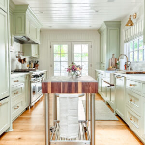 Green galley kitchen with butcher block rolling island.