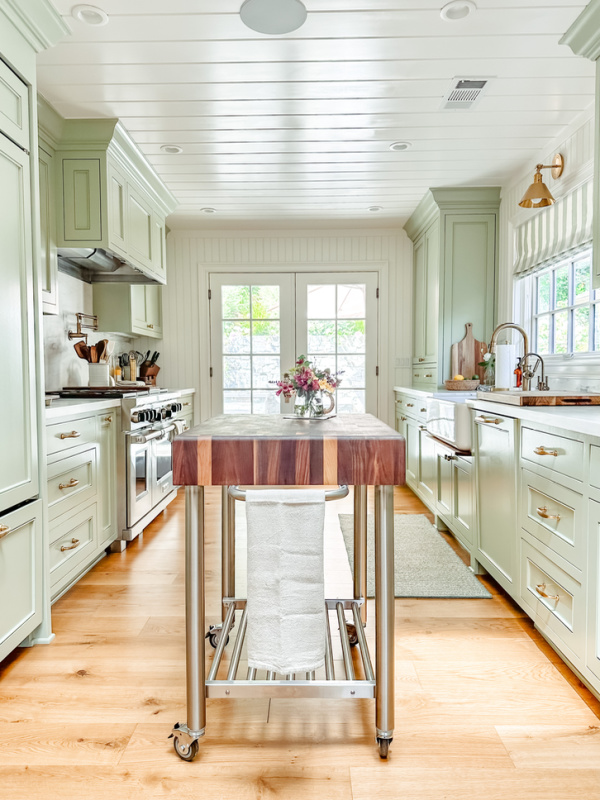 Green galley kitchen with butcher block rolling island.