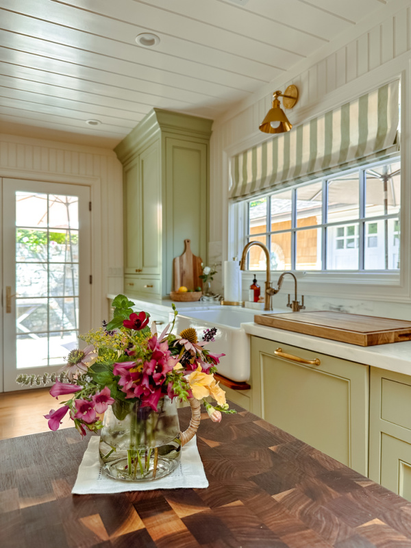 Green Kitchen with bouquet of flowers on walnut island.