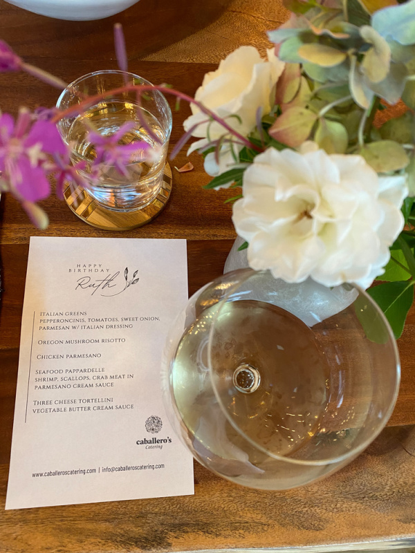 Dinner menu, flowers and wine glass on table.