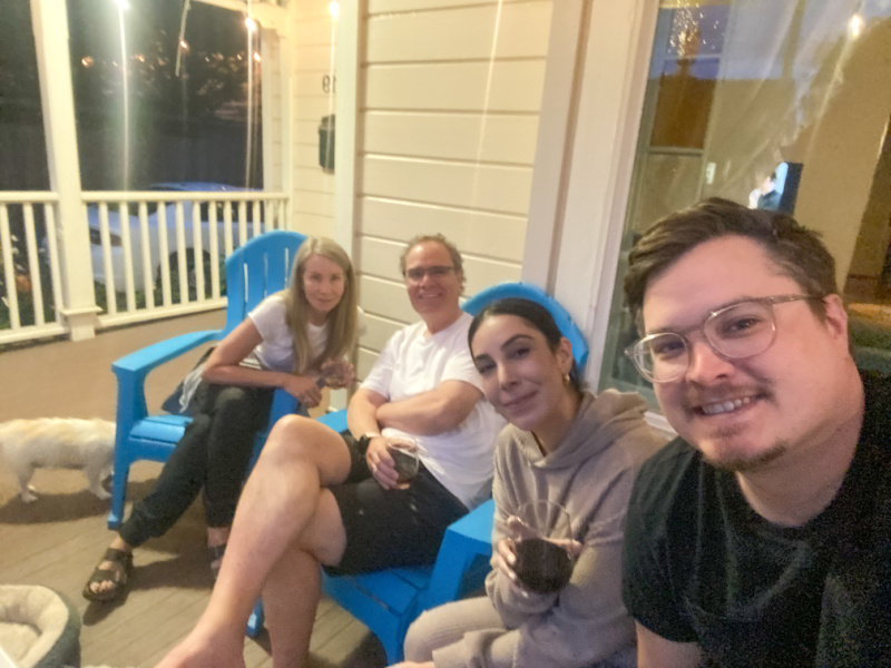 Two couples sipping wine on front porch.