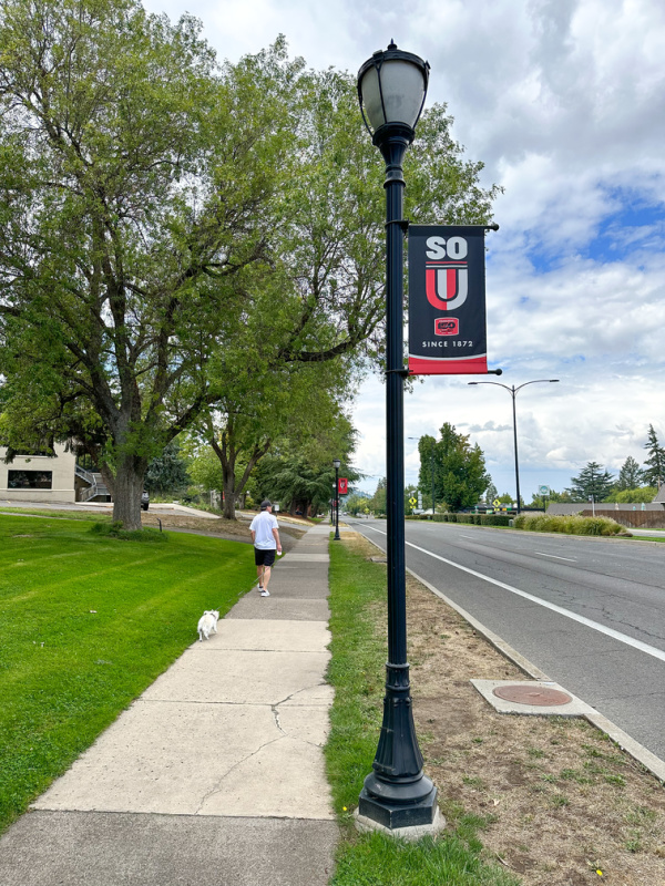 Man walking dog in front of Southern Oregon University.