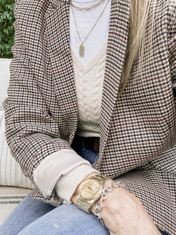 Woman wearing plaid jacket and gold Rolex.