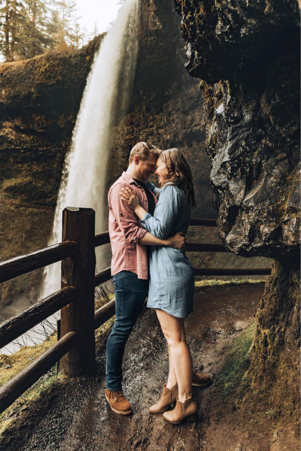 Couple posing in front of waterfall.