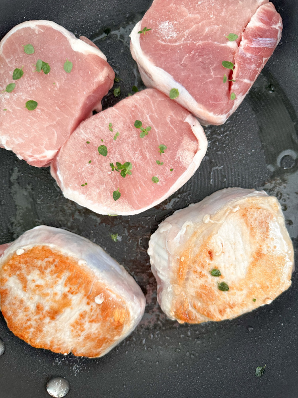 Pork chops browning in pan.