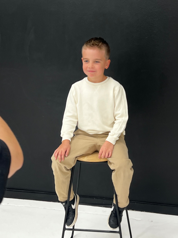 Seven year old boy sitting on stool for portrait.