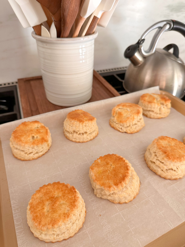 Baked biscuits on sitting on stove top on baking sheet.