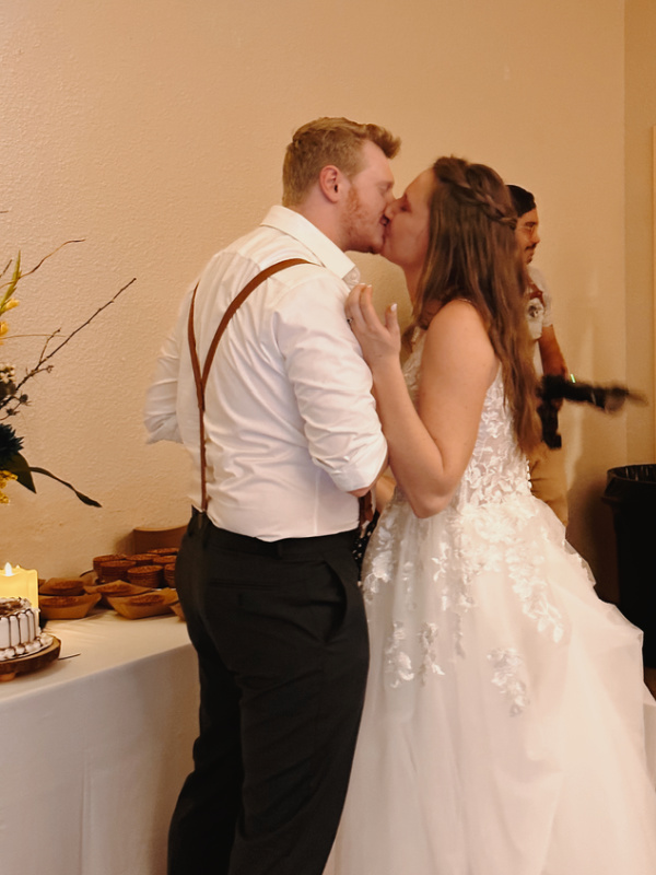 Couple kissing after eating wedding cake.