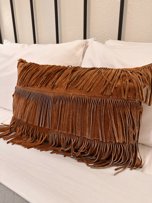 Leather fringe pillow on bed at Stables Inn.