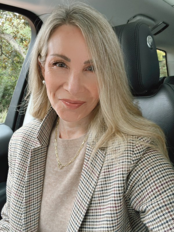 Woman taking selfie in car wearing camel Quince cashmere sweater and houndstooth blazer.