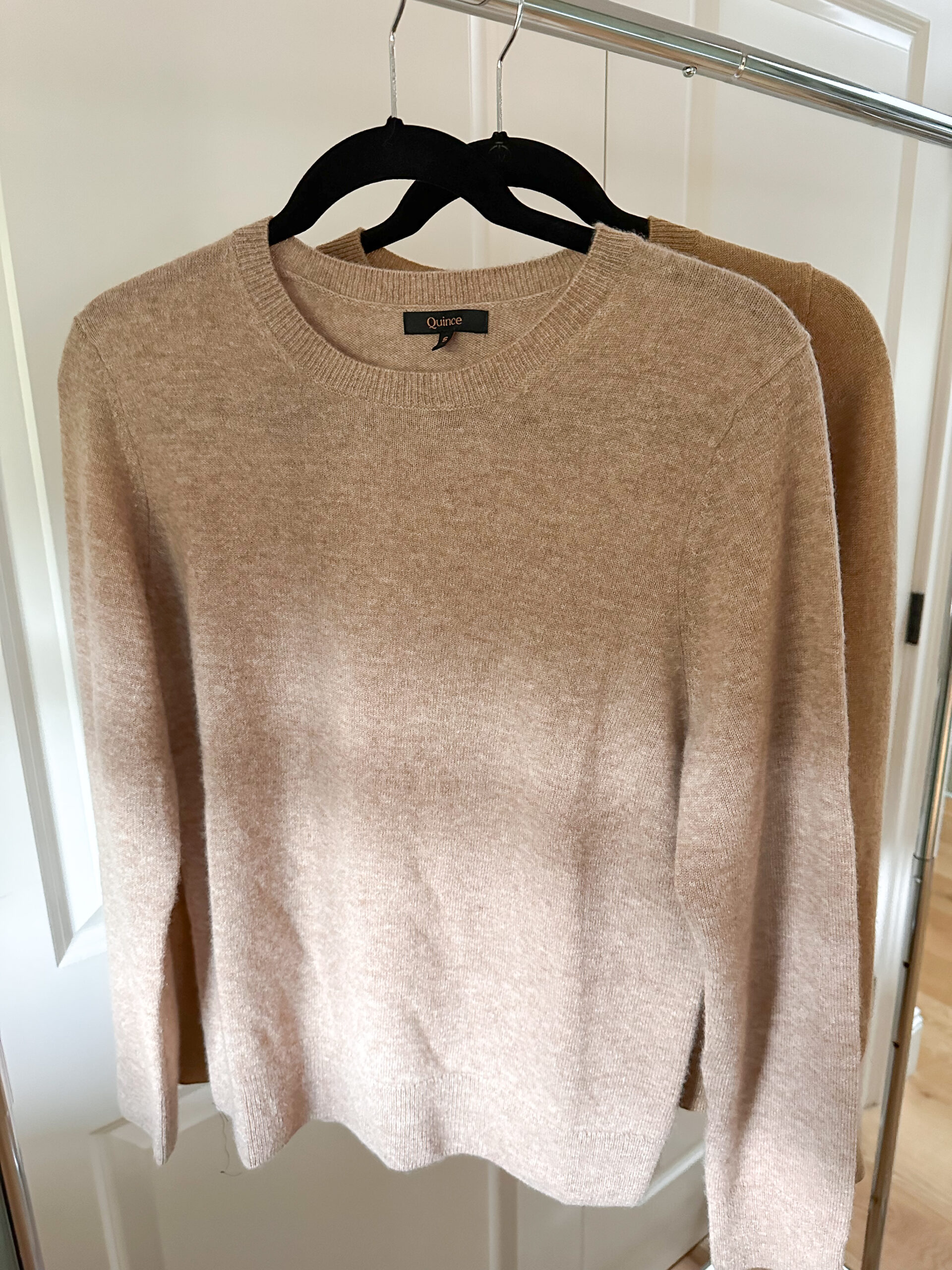 Two cashmere sweaters hanging on rack.