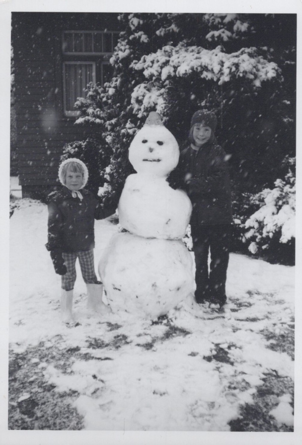 Two children standing on either side of Snowman in the 1970's.
