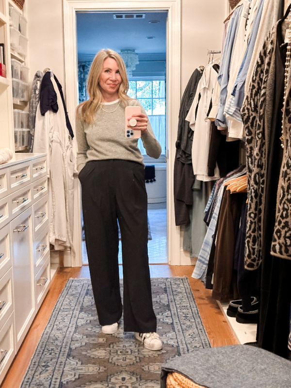 Woman taking a closet selfie wearing black trousers, adidas and gray cashmere sweater.