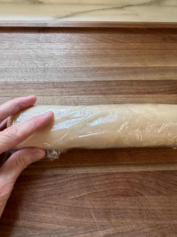 Hand resting on rolled cookie dough.