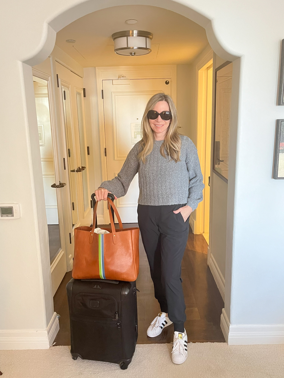 Woman standing in Casa Del Mar hotel room with carry on luggage.