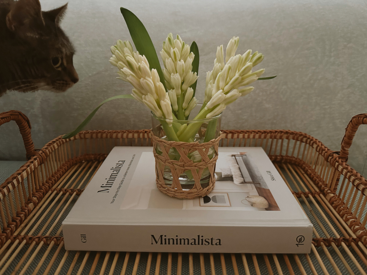 Minimalista book in wicker tray with small bouquet on top.