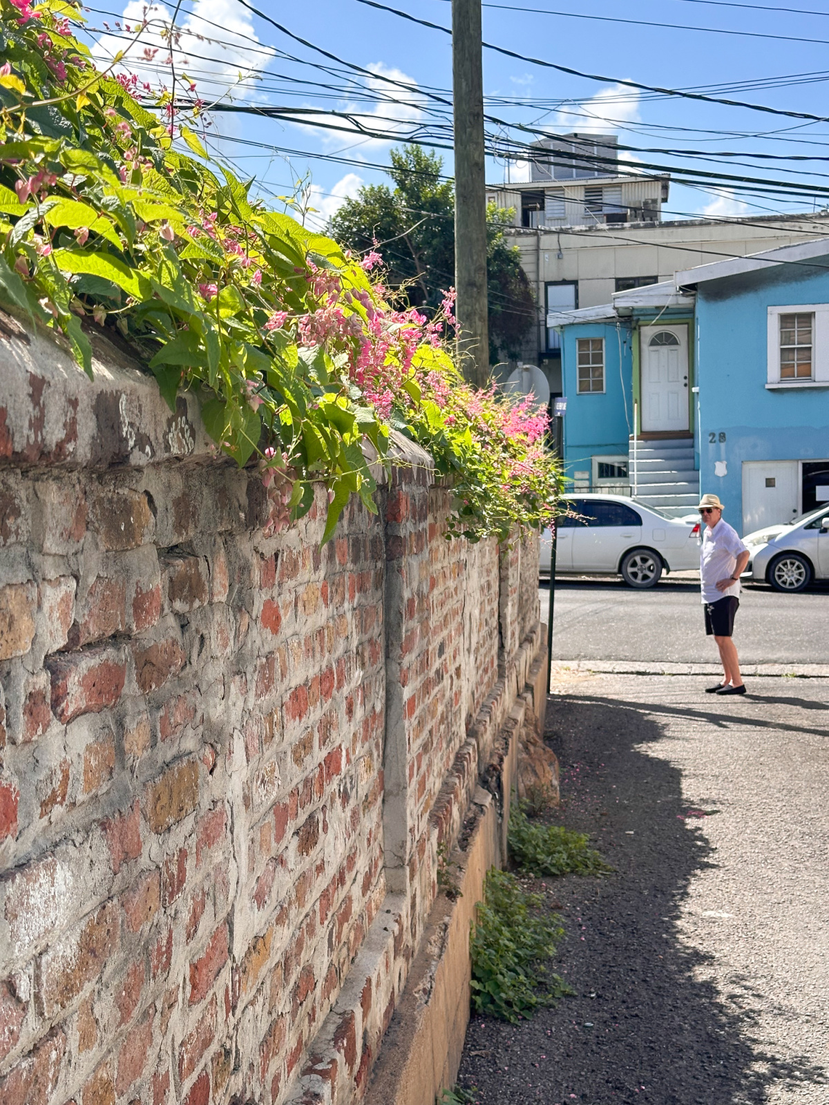 Man standing at end of path next to brick wall at St. John's Church, Antigua.