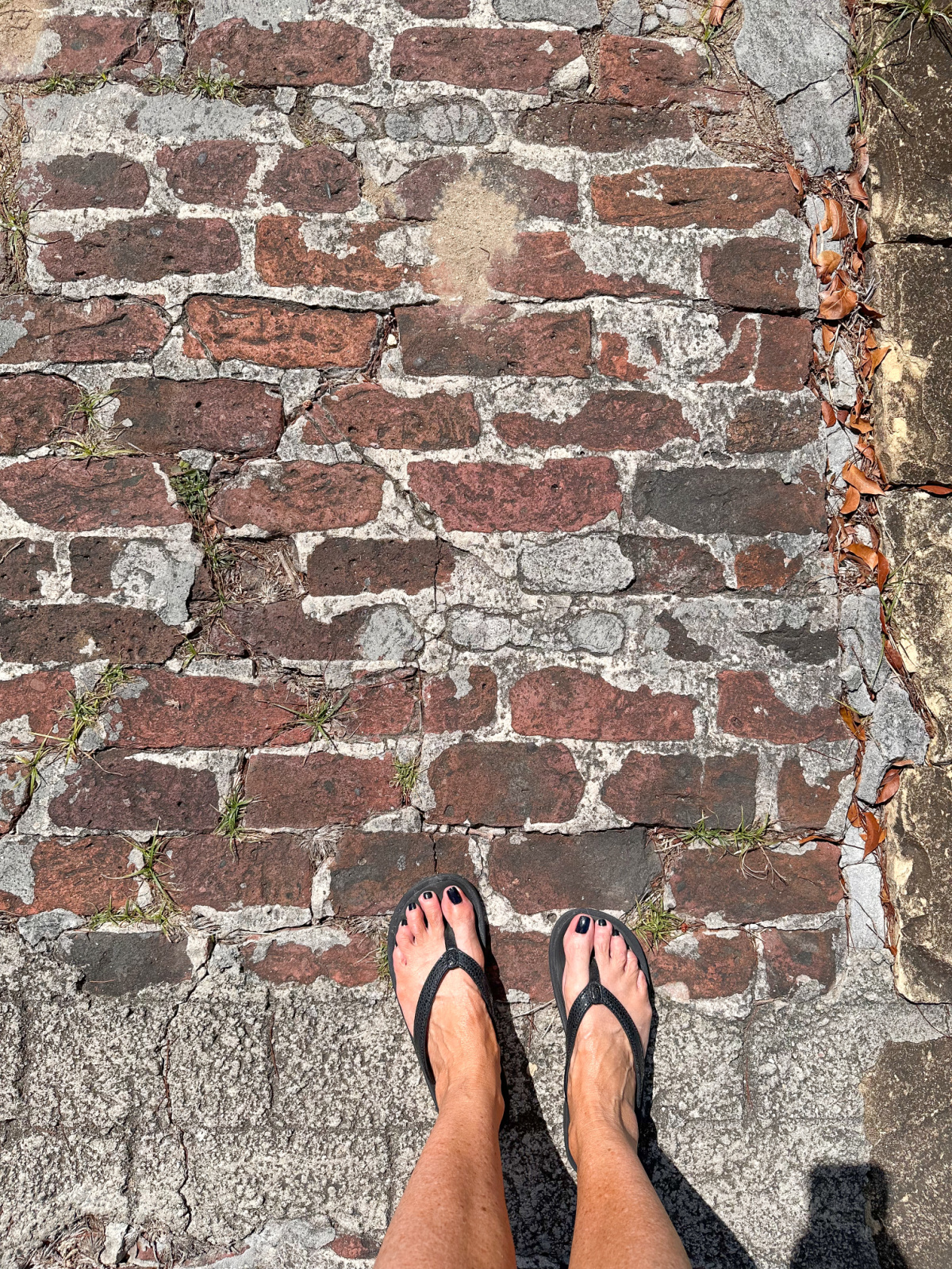 Flip flopped feet on old brick path at St. John's Cathedral, Antigua.