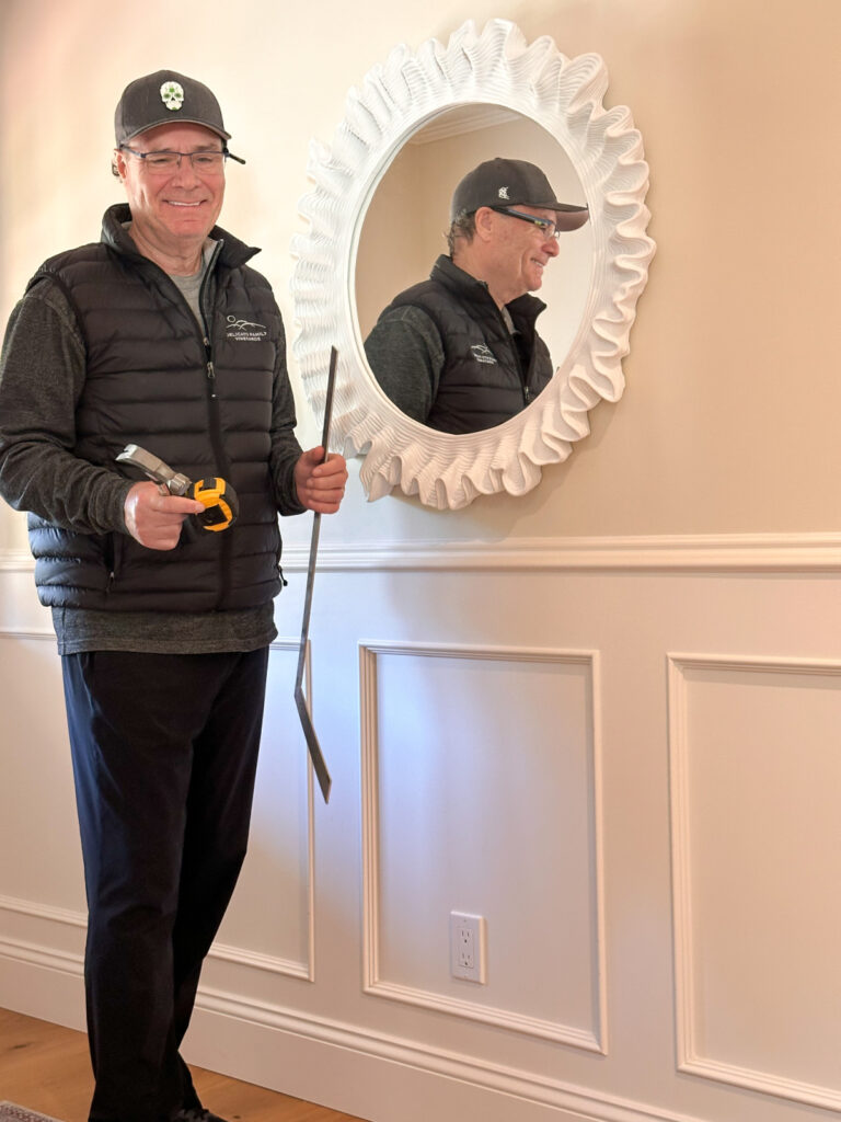 Man holding tools for hanging mirror.
