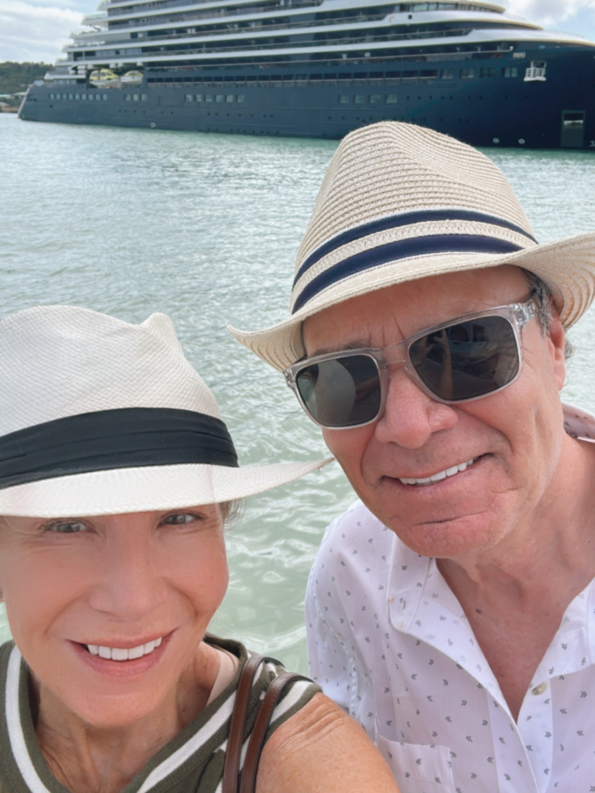 Couple taking selfie with Evrima yacht in background.