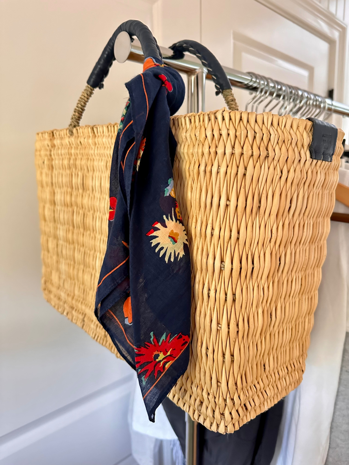 Basket bag and scarf hanging on rolling rack.