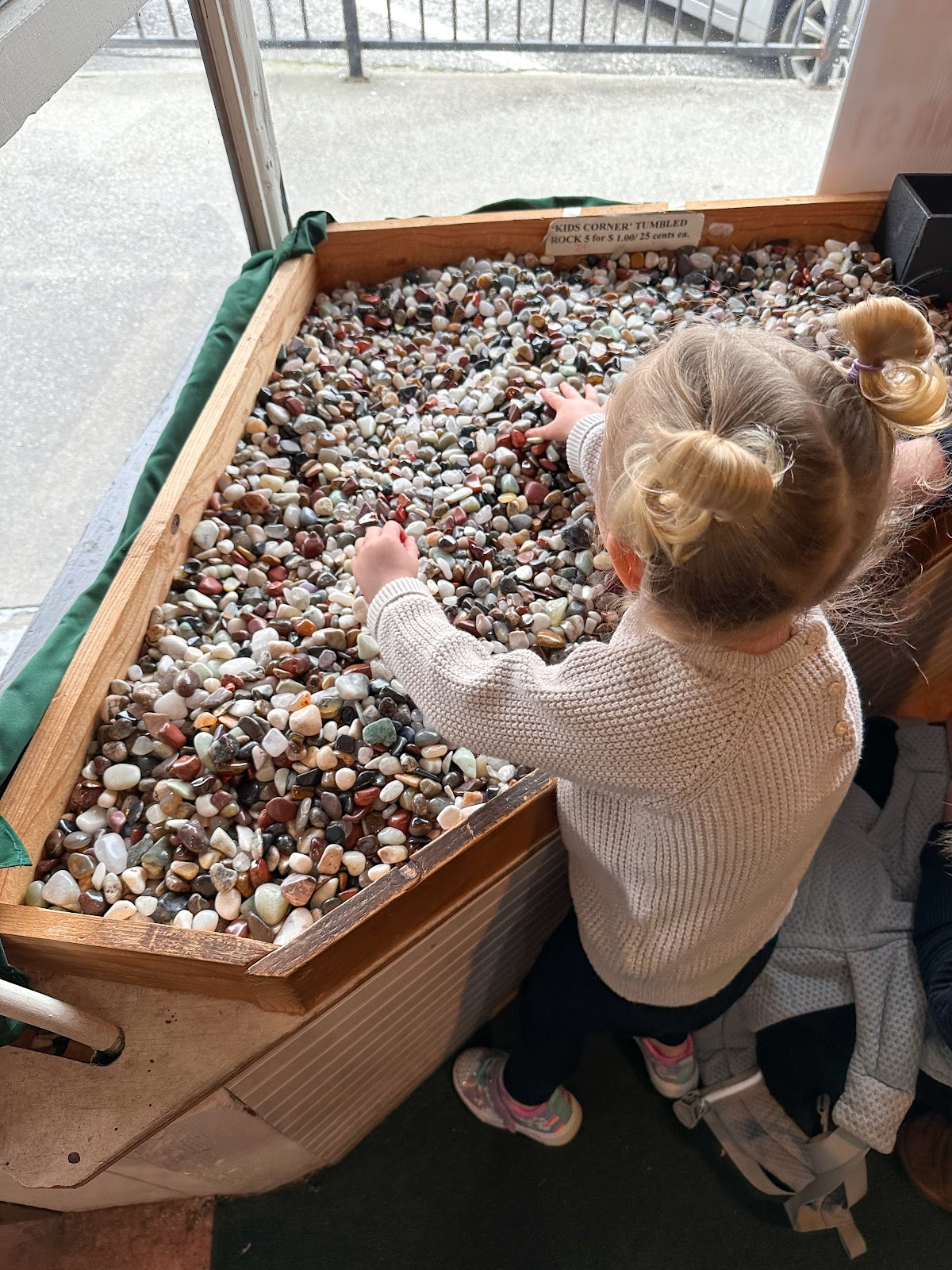 Little girl playing with bin of rocks.