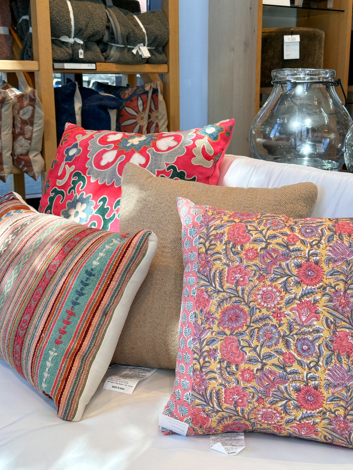 Colorful outdoor pillow display on sofa at Pottery Barn store.