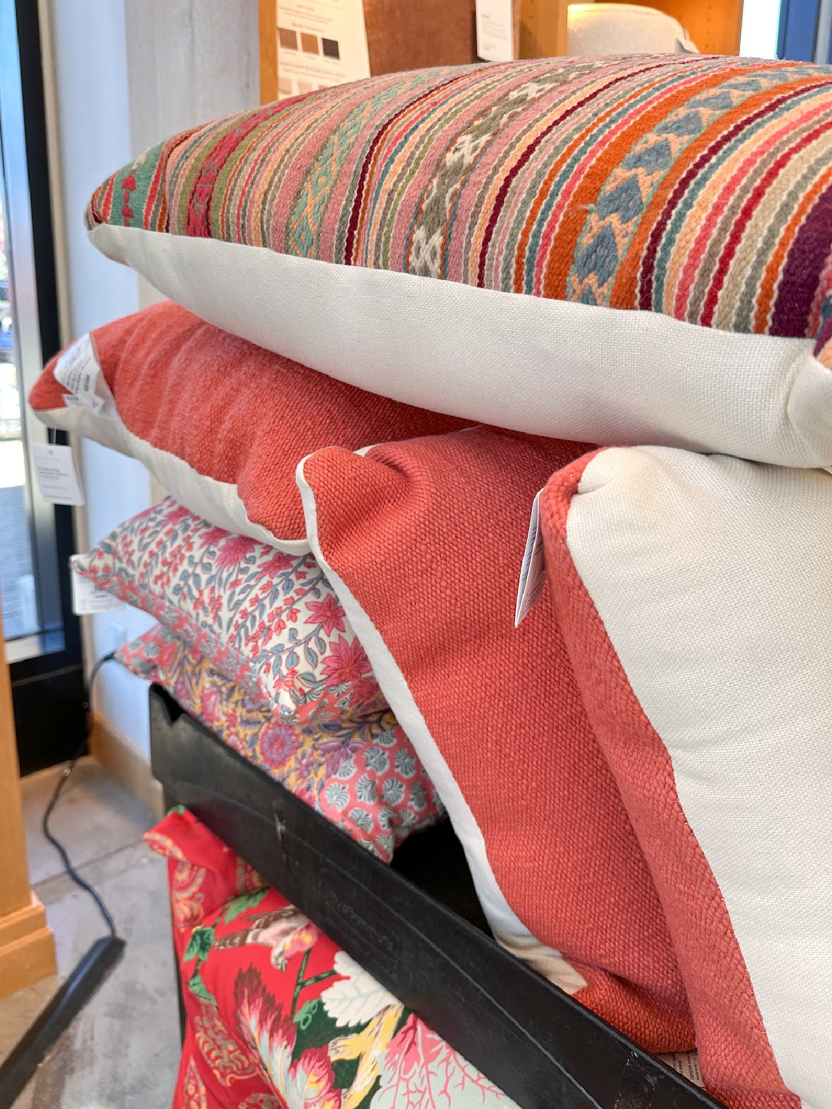 Coral and floral outdoor pillows on rack at Pottery Barn.