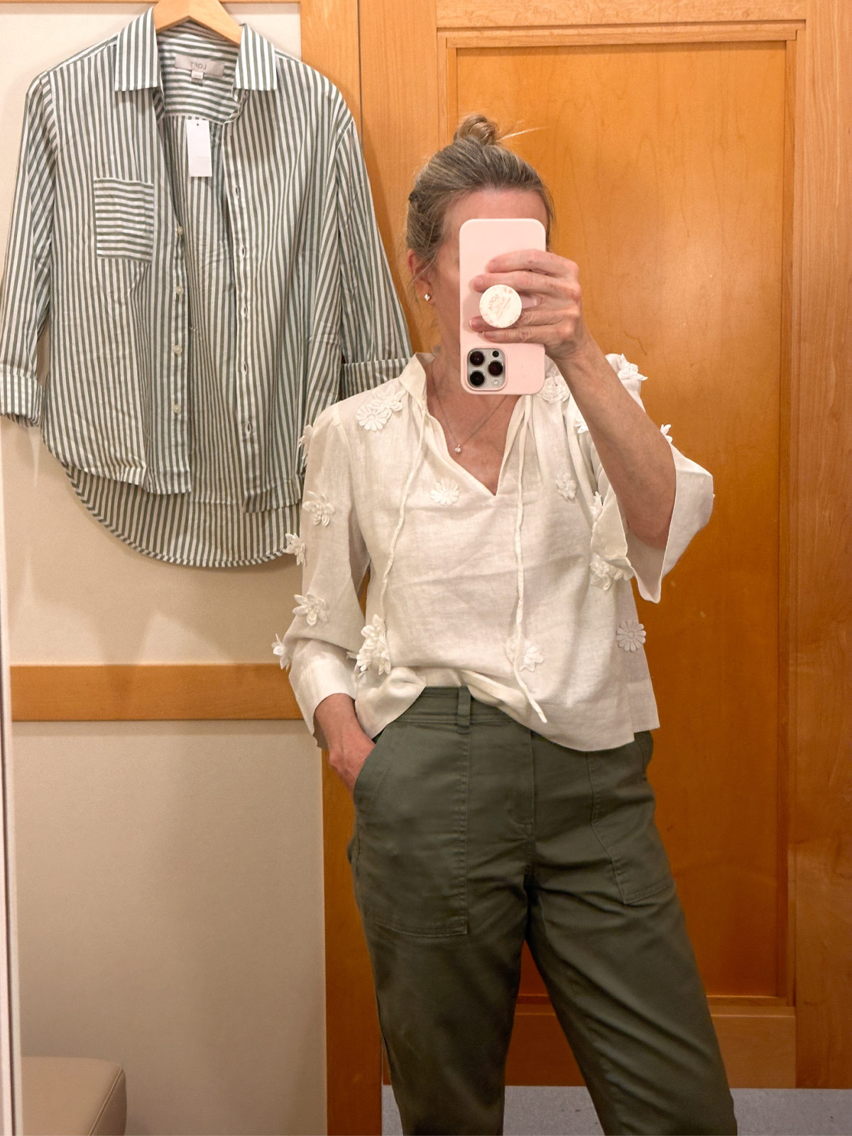 Woman taking selfi in dressing room mirror.