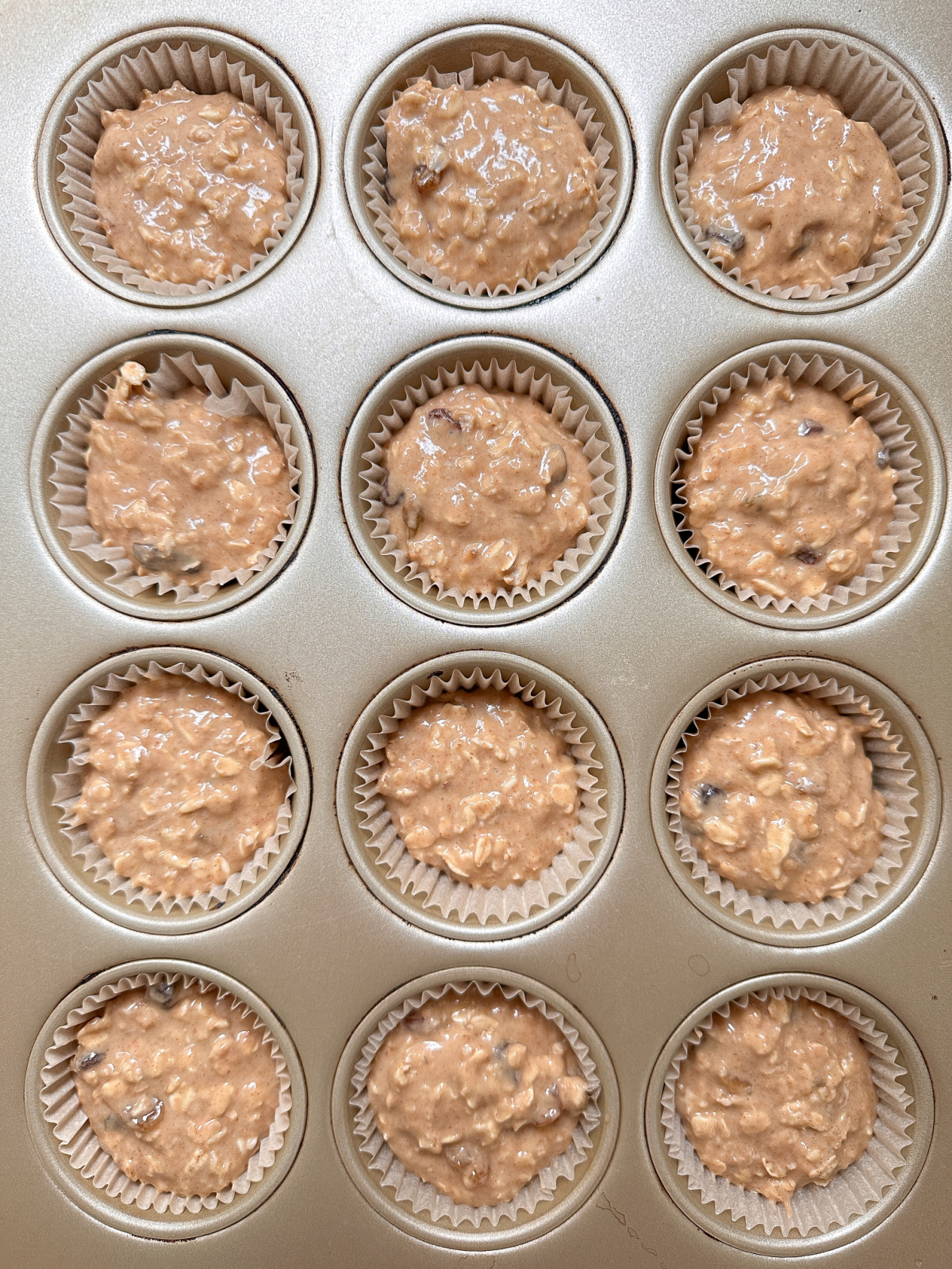 Oatmeal muffin batter in baking cups.
