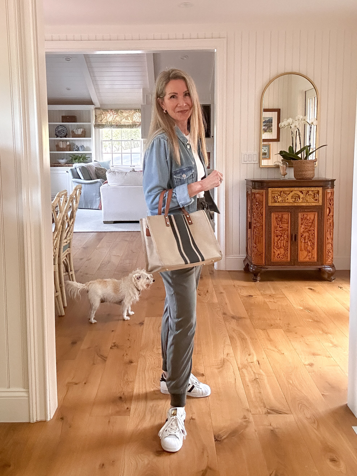 Woman wearing green khakis, white tee and denim jacket with striped bag.