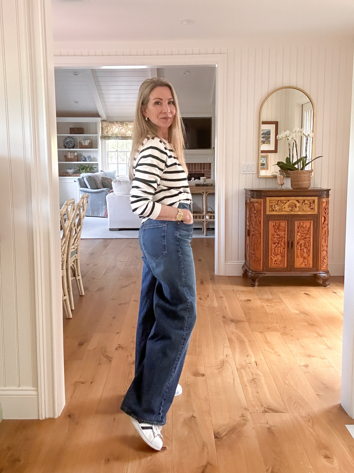Woman wearing cropped, striped sweater and wide leg denim with Adidas Superstars.