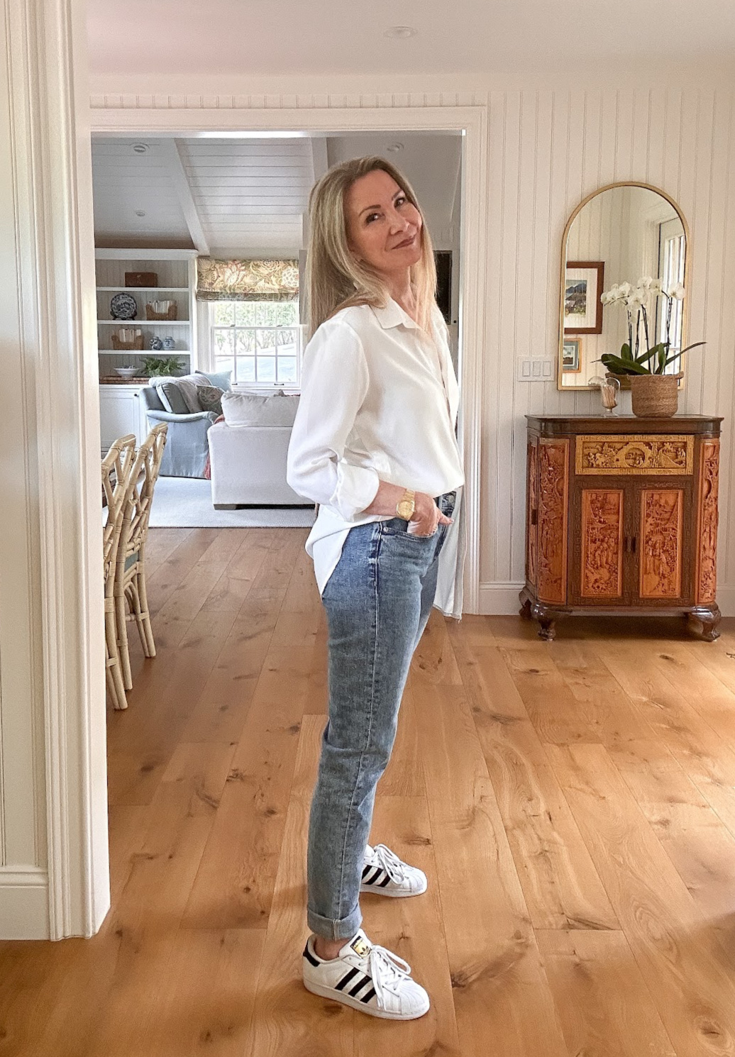Woman wearing white shirt and jeans with Adidas Superstars.