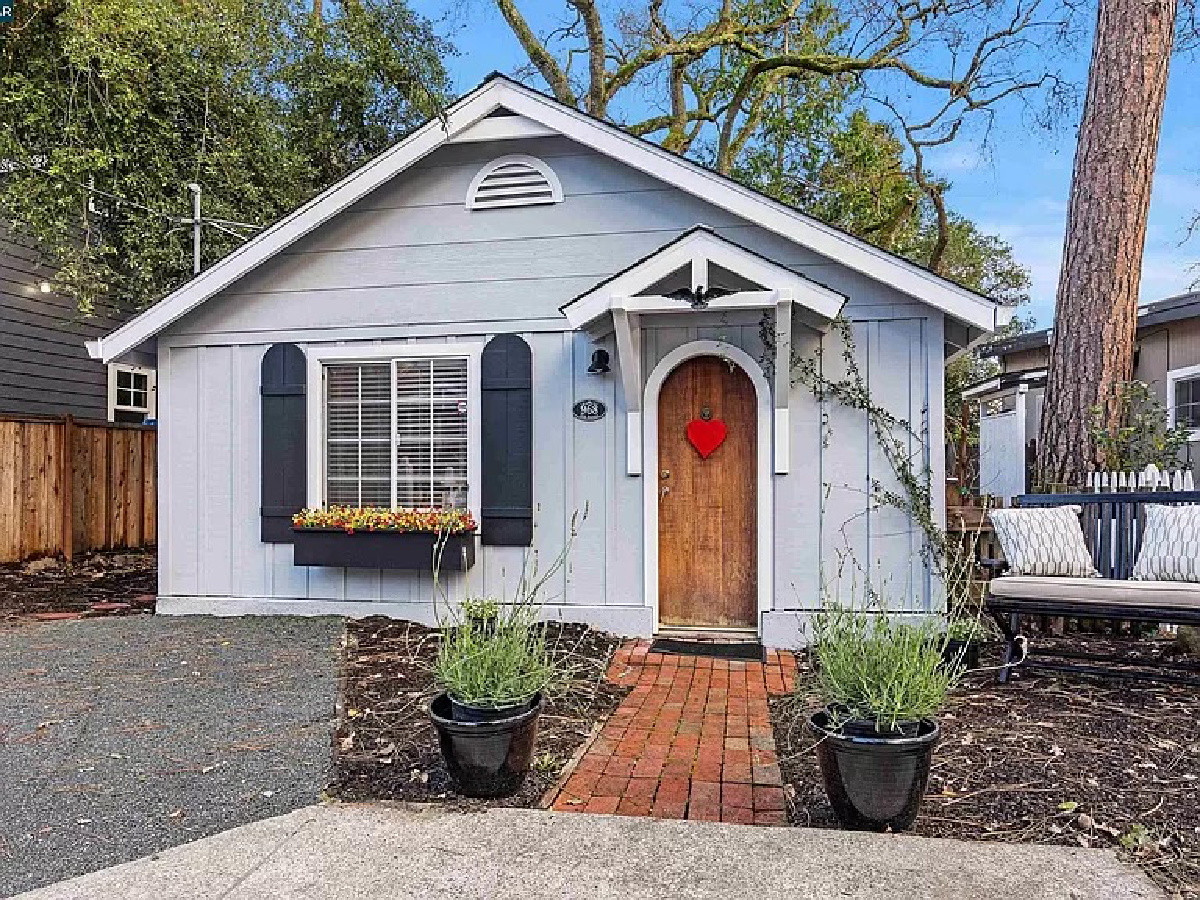 Tiny blue cottage with arched wood door with red heart.