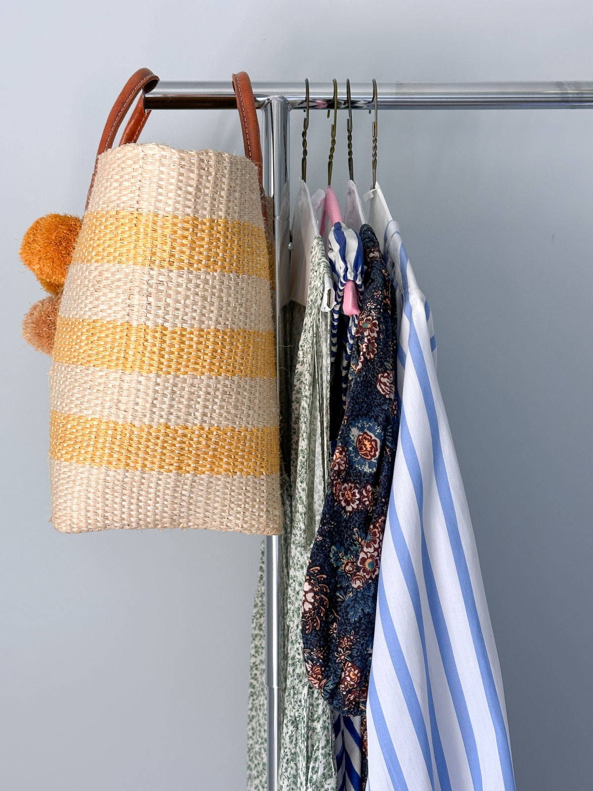 Mar Y Sol tote in yellow and white stripes hanging on rack next two summer dresses.