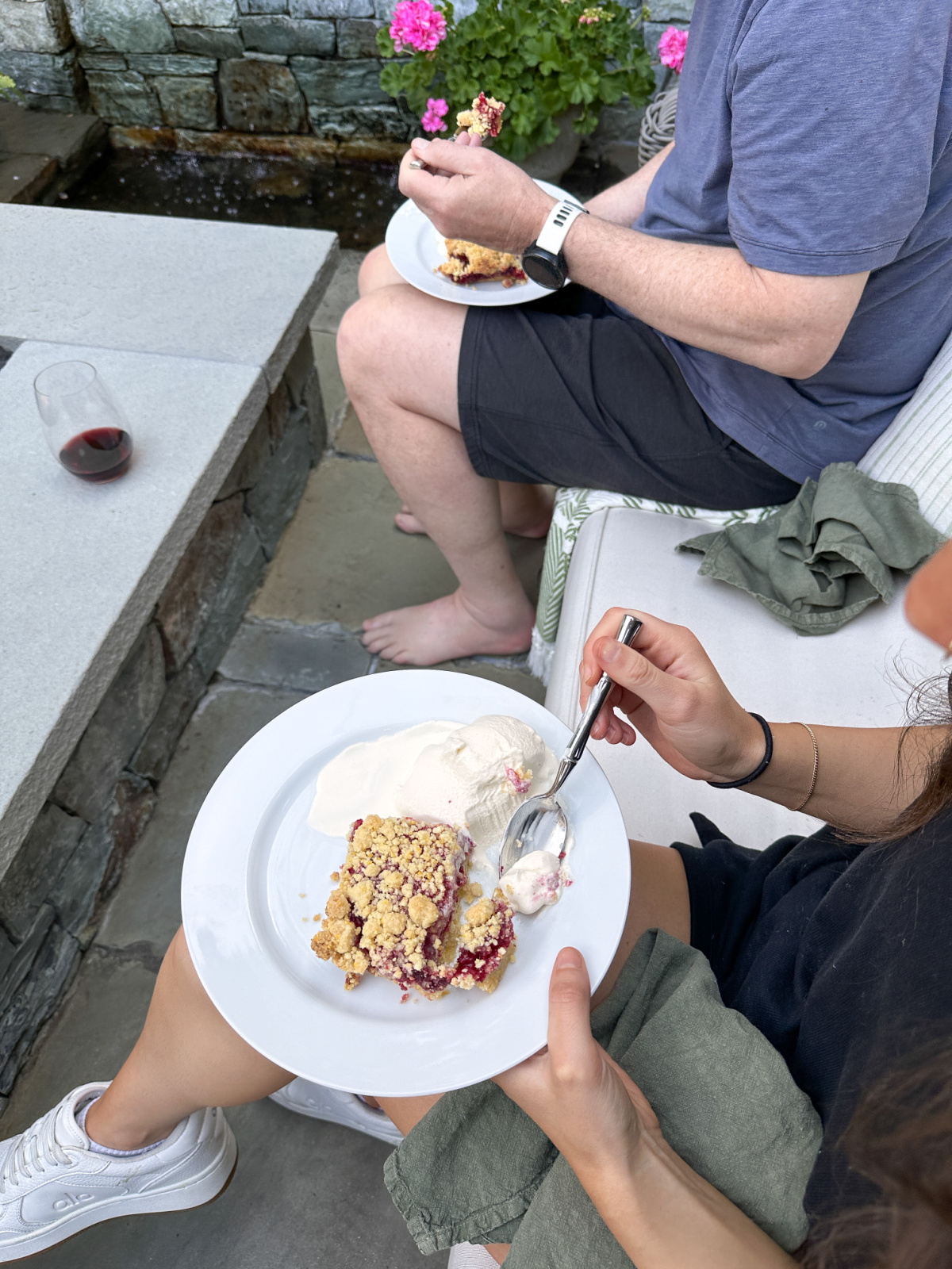 Overhead shot of man and woman sitting outside with dessert plates in their laps.